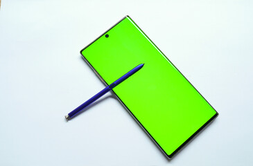 Smartphone mockup with green screen, stylus pen on the side, top view, isolated on white background