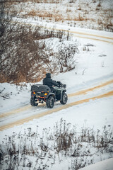 a rider on an ATV rides on a winter road