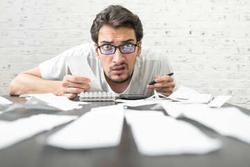 Close up of unhappy man sitting at the table, stressed and confused by calculate expense from invoice or bills, have no money to pay mortgage or loan. High prices and spending money concept