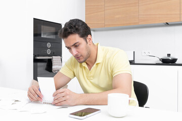 Young handsome man calculating his expenses, costs and monthly spendings	