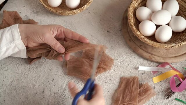 Cutting old nylon stockings with scissors - preparation for dyeing Easter eggs with onion peels