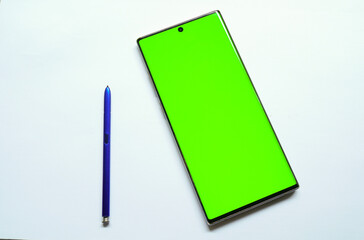 Smartphone mockup with green screen, stylus pen on the side, top view, isolated on white background