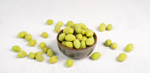 Pile of green wasabi coated peanuts in a bowl, spicy snack, oriental food
