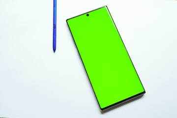 Smartphone mockup with green screen, stylus pen on the side, top view, isolated on white background