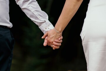 Closeup shot of the bride and groom holding the hands with wedding rings