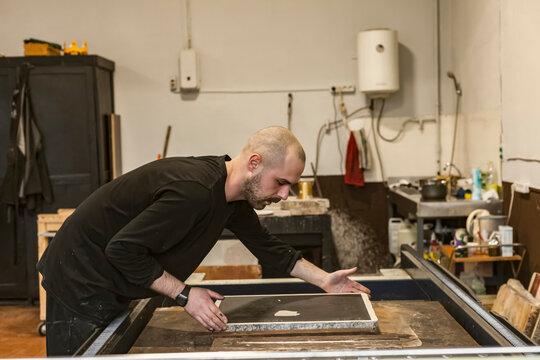 The artist placing a Lithographic limestone on a lithographic press or rolling press used for creating lithography in an art workshop.