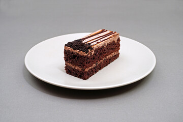 Piece of cake or pastry in white plate on grey background