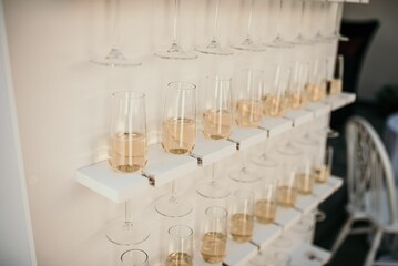 Bunch of glasses full of champagne hanging from the wall on the blurred background