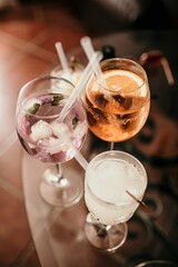 Vertical closeup shot of three glasses of drinks placed on a glass table
