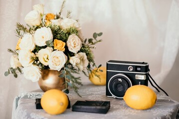 Closeup shot of a small table decorated with a bouquet of flowers, a camera, and lemons
