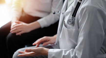 Unknown doctor and patient discussing current health examination while sitting at sofa, closeup. Medicine concept