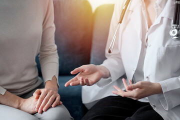 Doctor and patient discussing current health examination while sitting at sofa in clinic office, closeup. Medicine concept