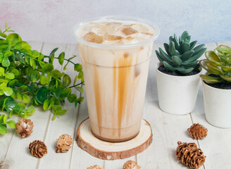 Hand-fried brown sugar milk tea served om disposable glass isolated on wooden board top view of hong kong drink