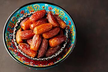 Dried dates in bowl on a dark background. Bowl of pitted dates. Food for Ramadan. Top view. Copy space