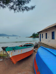 Fototapeta na wymiar fishing boats on the beach next to the rustic house on a cloudy day