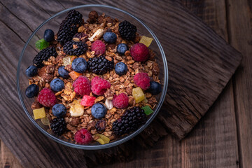 Large glass bowl with berries and granola. Beautiful and juicy forest berries. Granola and berries on the table.
