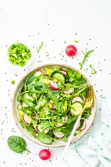 Fotobehang Green salad with spinach, arugula and radish with olive oil on white table. Top view with copy space. © nadianb