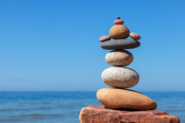 Fototapeta na wymiar Rock zen pyramid of stones of different shapes on a background of blue sky and sea.