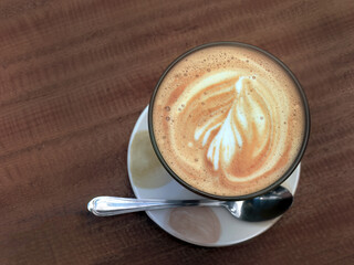 High angle view A cup of coffee with spoon on wooden table, latte art, coffee art, retro style, cafe tone, Korean cafe