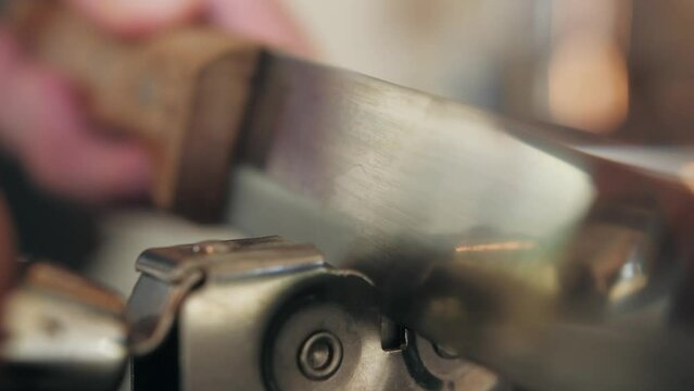 Man Sharpening the knife with a whetstone on a wooden background close up.