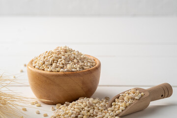 Uncooked barley, pearl barley in wooden bowl on wood table with copy space