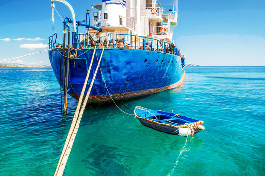 The serenity od a sunny afternoon in the Greek Islands:   some ship and a  boat  moored  to it, the  sparks of the sun on the water,  a light breeze, the end of summer not  so hot