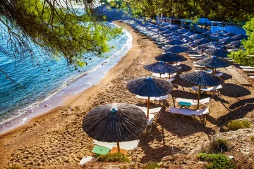 Fotobehang Camps Bay Beach, Kaapstad, Zuid-Afrika Amazing emerald water of small bay in Greek islands (Spetses)  and idyllic sandy beach  with beach chairs, tents and pine treess  and small pine trees