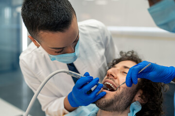 Female dentist specialist using dental drill, examining and working on patient's teeth, removing...