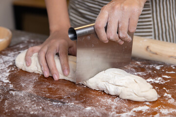Baker Hand Cutting Raw Dough with a Knife