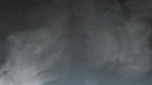 Gray smoke on a dark background, slow motion.