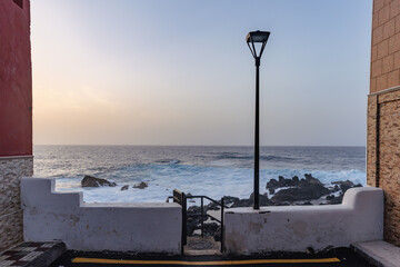 un lampadaire et un muret au bord des l'océan en fin de soirée, entre d eux murs