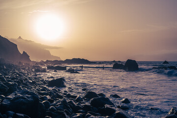 la côte littorale sous un coucher de soleil orange avec une plage de rochers
