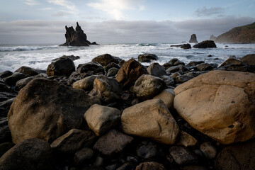Fototapeta na wymiar vue d'une plage avec de gros rochers et un îlot pointu au large
