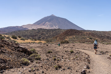 deux randonneurs sur un sentier avec un volcan en arrière plan