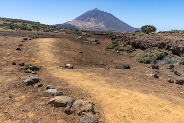un sentier de terre ocre avec un volcan en fond