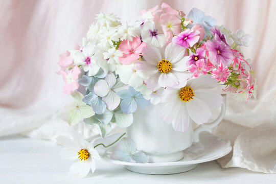 Colorful bouquet with hydrangea, cosmos flowers, phlox in a cup on a white table. Greeting card for the holiday.