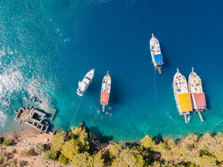 Aerial view of tour boats and private yachts and swimmers enjoying the beautiful Kleopatra Hamamı Cove, located between G&ouml;cek and Dalaman, Turkey, known for its crystal-clear waters and ancient ruins.