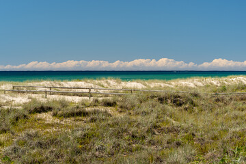 View across sand dunes to the ocean, with cloud on the horizon, under a clear blue sky. Kirra Beach, Gold Coast, Queensland, Australia. 