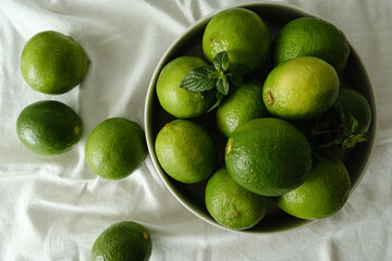 foto superior de limões e hortelã sobre mesa com toalha branca