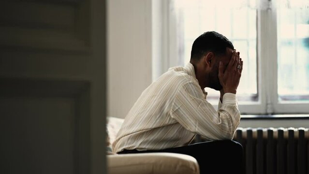 Frustrated Aggressive man hitting couch with hand feeling angry about helpless about difficult situation. Candid dramatic moment of frustration