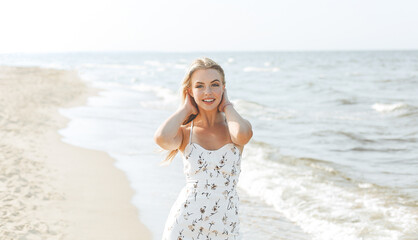 Fototapeta na wymiar Happy blonde woman in free happiness bliss on ocean beach standing straight and posing