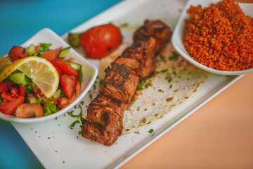 Angled Side View of Authentic Turkish Lamb Shish: Succulent Meat, Grilled Skewers, Couscous and Salad Sides, Flavorful Combination, Gourmet Food, Delicious Meal, Mediterranean Cuisine