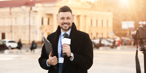 Male journalist with microphone outdoors