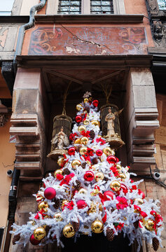 A Christmas tree with white and yellow balloons under medieval balcony of Alsatian house in Strasbourg, France