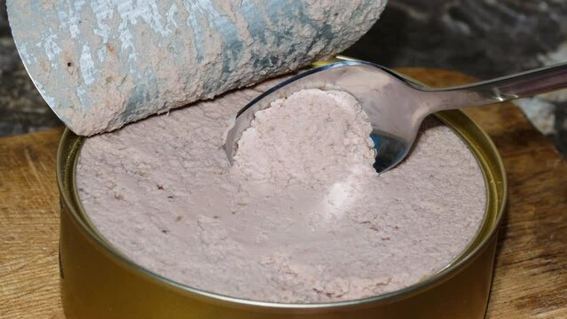 Scoop up the pate with a spoon. Liver pate is eaten from a tin can. The meat pate is scooped by hand with a teaspoon from a tin can. Freshly prepared finely chopped minced pork and beef meat. Close-up