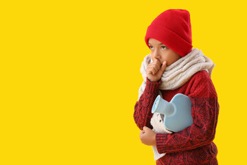 Ill African-American boy with hot water bottle coughing on yellow background