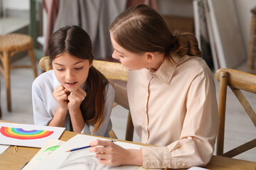 Drawing teacher giving private art lesson to little girl in workshop