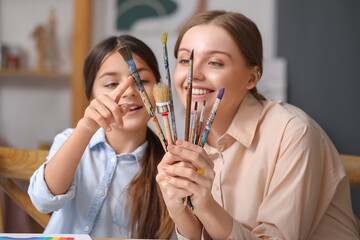 Little girl and her drawing teacher with paint brushes in workshop, closeup