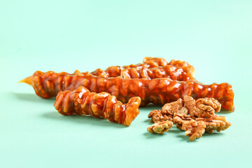 Tasty churchkhela and walnuts on color background