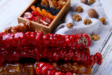 Board with delicious churchkhela and box of ingredients on white wooden background